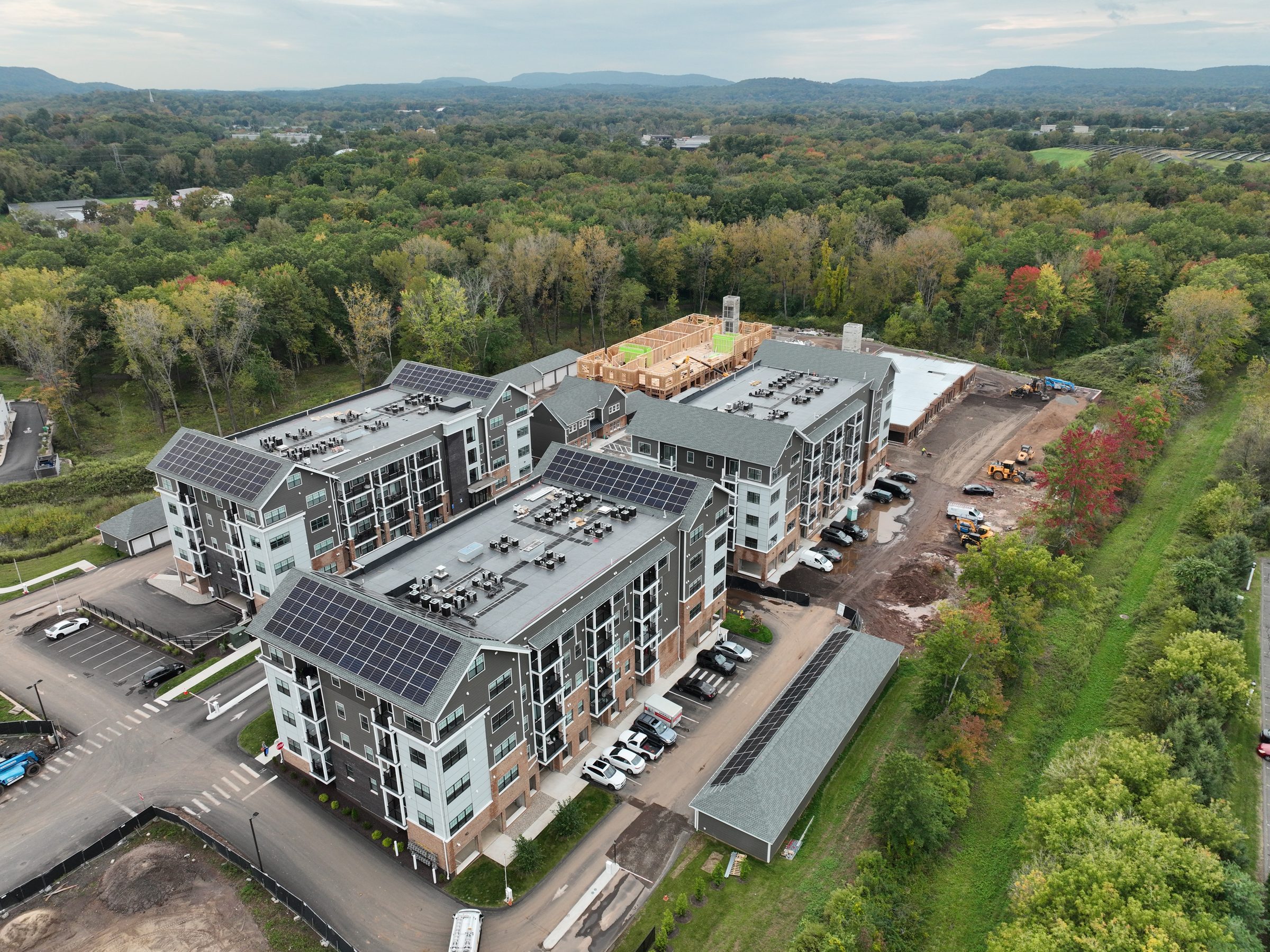 Aerial oblique of a multifamily construction site, completed buildings in the foreground and wood framing in progress beyond